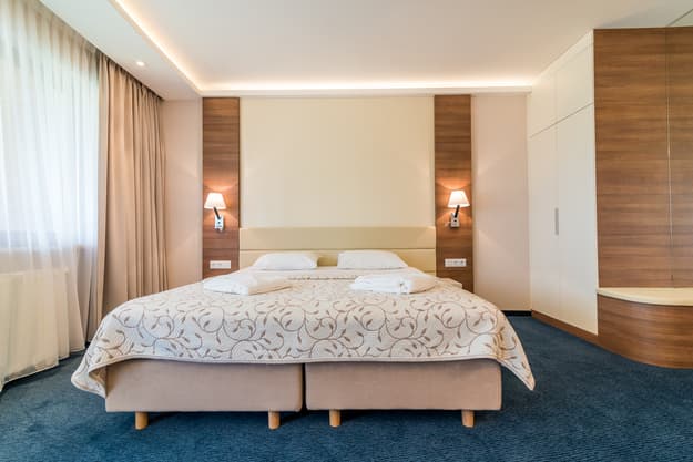 Łóżko dwuosobowe w Apartamencie Zdrojowym 323 z hotelową pościelą i dwiema lampkami nocnymi po bokach
